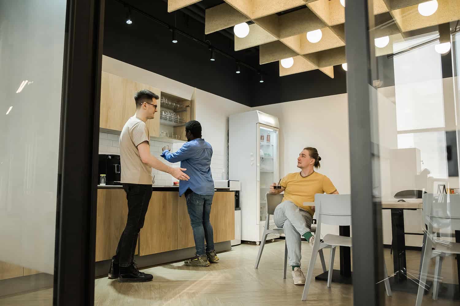 Group of young people talking and smiling during a coffee break in a modern office