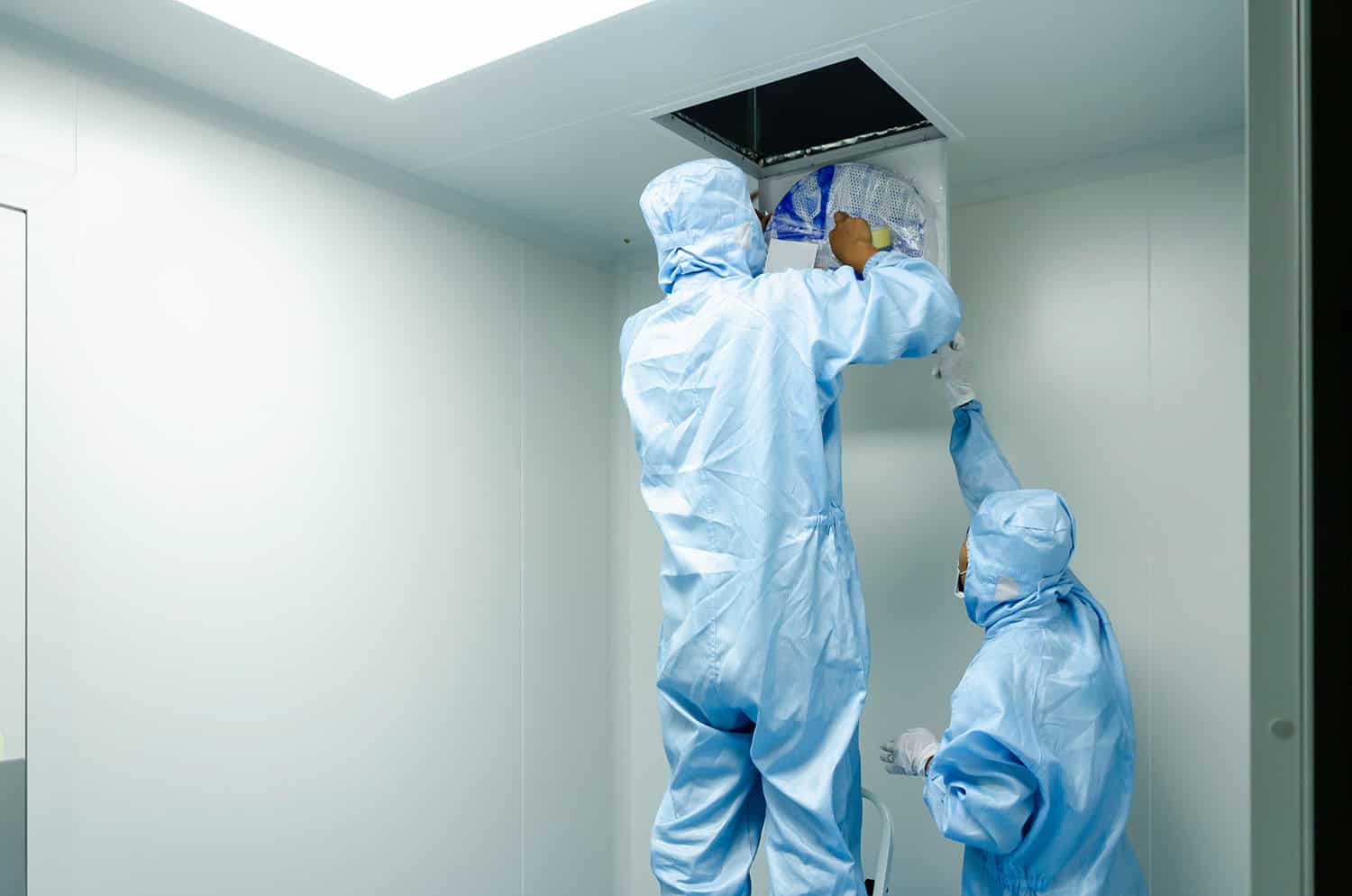 Two people in sanitary gowns testing hospital air filter for cleanliness