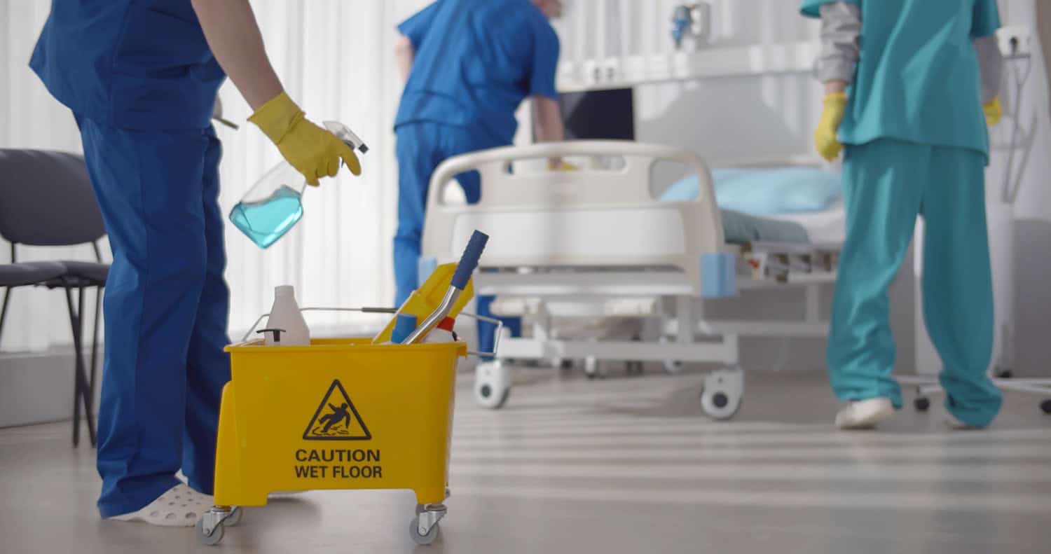 A hospital room being cleaned with bed in background