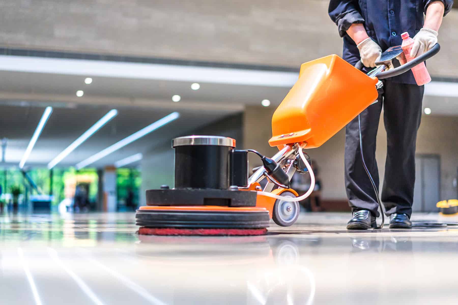 Cleaner using floor scrubber machine on sparkling shopping centre floor