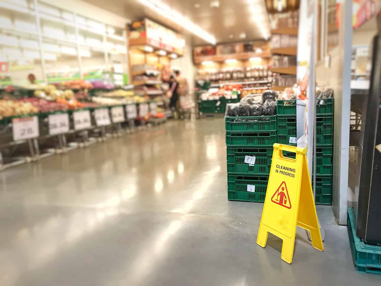 Yellow 'Cleaning in progress' sign in produce section of a supermarket