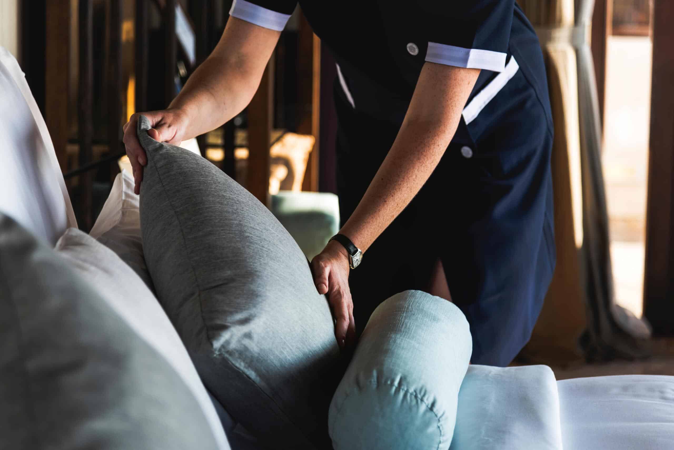 Hotel & Hospitality Cleaning Hotel cleaner fluffing blue couch cushion