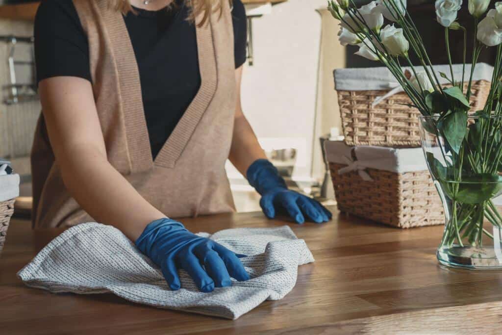 cleaner wiping down timber bench with cloth