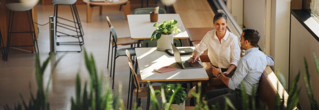 woman sitting at a table with a colleague in a coworking space